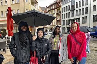 Kursteilnehmerinnen in der verrergneten Altstadt Jugendliche in Regenjacken und unter einem Regenschirm in der Altstadt von Bautzen