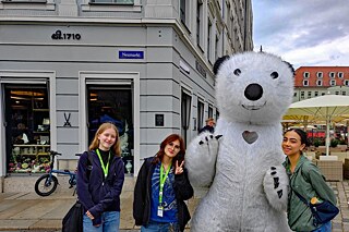 Drei junge Frauen stehen neben einem Eisbären und lächeln in die Kamera.