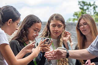 Junge Frauen bewundern eine Biene auf der Hand eines Mannes.