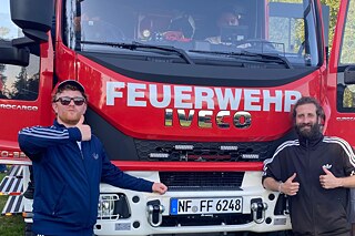 Zwei Männer vor einem Feuerwehrwagen