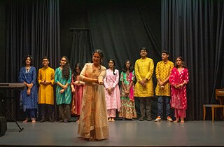 Jugendliche aus Indien in Tracht stehen auf einer Bühne.
