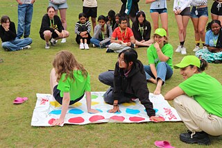 Jugendliche spielen Twister auf einer Wiese.
