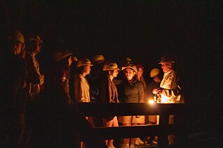 Jugendliche lauschen Geschichten in einem alten Bergwerk.