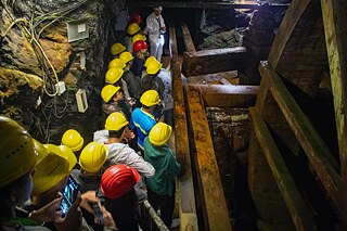 Jugendliche bestaunen ein altes Wasserrad in einem Bergwerk.
