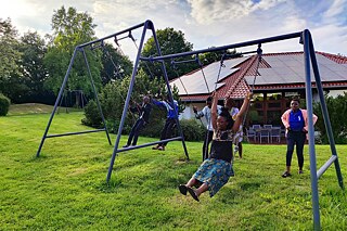 Jugendliche schaukeln auf einer Wiese.