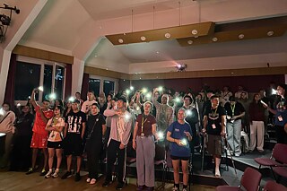 Jugendliche singen und haben die Lampe ihrer Smartphones an.