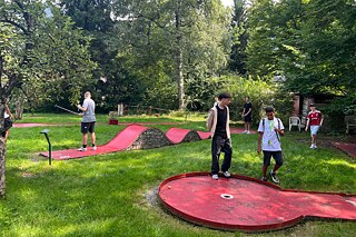Jugendliche spielen Minigolf.