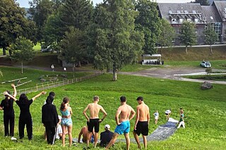 Jugendliche haben Spaß an einem Hang mit einer improvisierten Wasserrutsche.