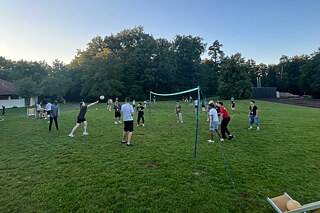 Jugendliche spielen Volleyball auf einer Wiese.