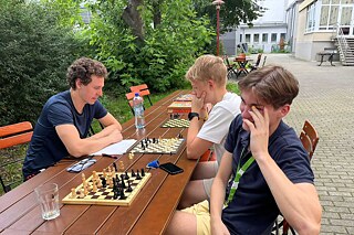 Junge Menschen in einem Garten spielen Schach.
