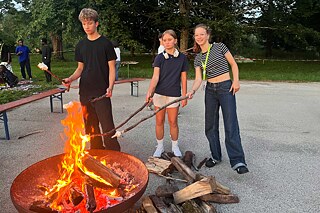 Jugendliche grillen Marshmellows über einem offenen Feuer.