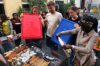 Junge Menschen wedeln Luft über einen Holzkohlegrill.