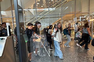Jugendliche hinter Sicherheitsglas in einem Flughafen