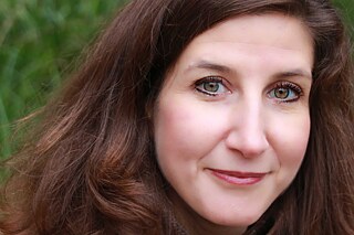 Porträt von Christina, im Hintergrund eine grüne Hecke