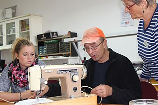 Frau Dietrich, Herr Lenz und Frau Nöth beim Reparieren der Nähmaschine