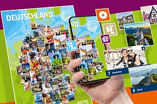 Eine Hand hält ein Smartphone, darauf sind mosaikartig angeordnet verschiedene bunte Fotografien. Im Hintergrund ist ein Poster mit dem Titel "Deutschland" zu sehen.