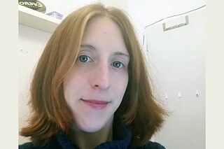 Frau mit roten Haaren und dunklem Pullover lächelt in die Kamera