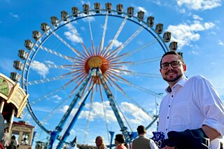 Ein junger Mann vor dem Riesenrad auf der „Wiesn“