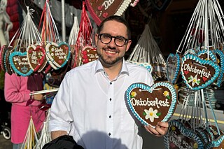 Junger Mann vor einem Stand mit Lebkuchenherzen