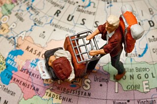 Die Figur eines Backpackers steht auf einem Globus