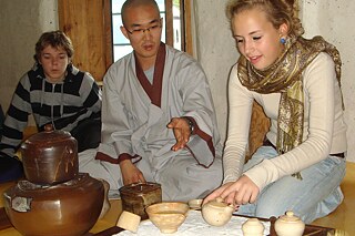 Eine Schülerin hilft einem Mönch bei einer traditionellen Teezeremonie.