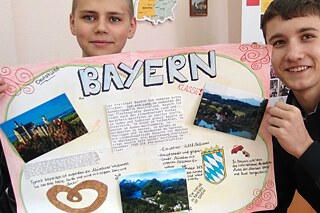 Zwei Jungen halten ein Plakat über Bayern hoch