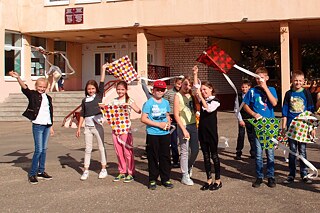 Fahnenschwenkende Kindern vor dem Schuleingang
