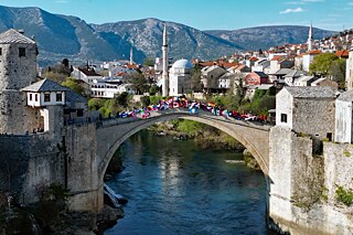 Schülerinnen und Schüler mit Flaggen auf berühmter Brücke von Mostar
