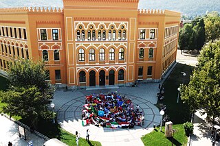 Schülergruppe mit Flaggen vor Schulgebäude