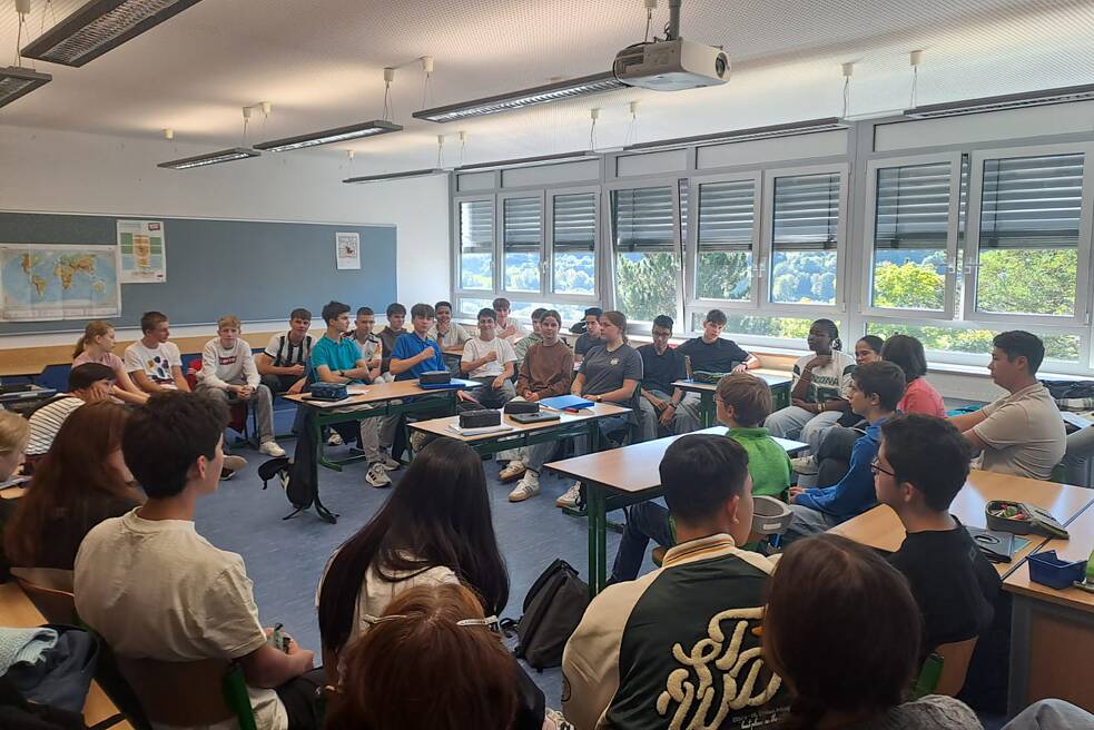 Schüler und Schülerinnen in einem Klassenraum unterhalten sich.