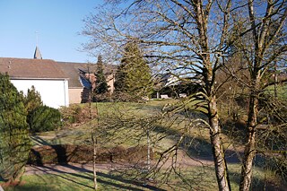 Grünes Gelände mit Schulkirche des Erzbischöflichen St.-Angela-Gymnasium