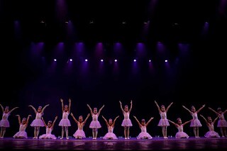Kleine Ballerinas tanzen auf einer Bühne.