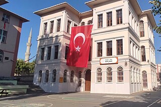 Helles Schulgebäude mit großer türkischer Fahne