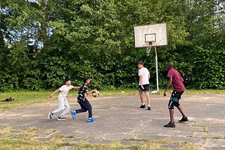 Jugendliche spielen Basketball im Freien.