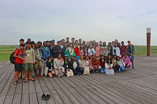 Jugendliche posieren auf einer Holzterrasse am Strand für ein Gruppenfoto.