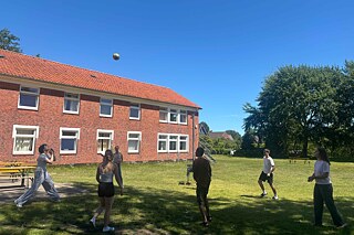 Jugendliche spielen Volleyball auf einer Wiese.
