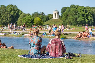 Menschen sitzen an einem See im Park.