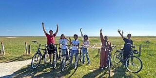 Jugendliche auf dem Fahrrad vor einer Strandkulisse
