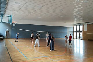 Jugendliche spielen Volleyball in einer Sporthalle.