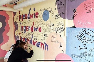 Jugendliche schreiben Abschiedsgröße an eine Wand.