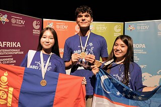 Gewinnerinnen und Gewinner der Internationalen Deutscholympiade 2026 zeigen ihre Medaillen.