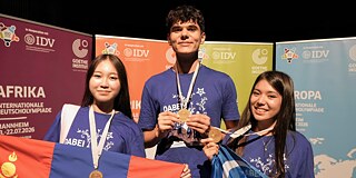 Gewinnerinnen und Gewinner der Internationalen Deutscholympiade 2026 zeigen ihre Medaillen.