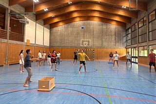 Jugendliche spielen Brennball in einer Sporthalle.