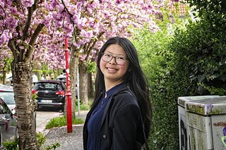 Eine junge Frau mit dunklen langen Haaren unter einem blühenden Kirschbaum