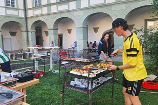 Ein junger Erwachsener steht am Grill.