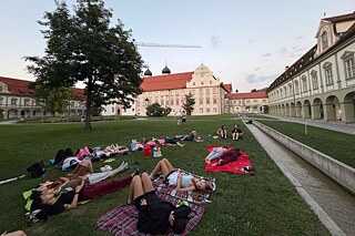 Jugendliche liegen auf der Wiese des Klosters und entspannen.