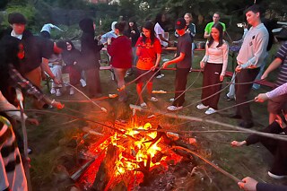 Jugendliche bei Stockbrot und Lagerfeuer