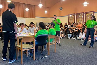 Jugendliche sitzen an einem Tisch und essen um die Wette.