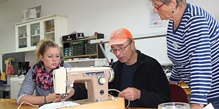 Frau Dietrich, Herr Lenz und Frau Nöth beim Reparieren der Nähmaschine
