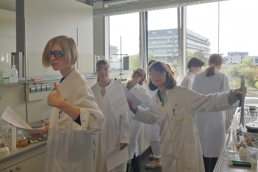 Schüler und Schülerinnen in Laborkittel und Schutzbrille